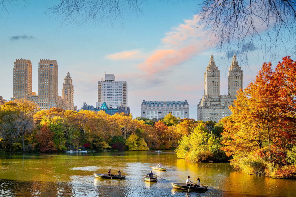 Boat riding in Central Park with luxury residential building in the back - on the Upper West Side.