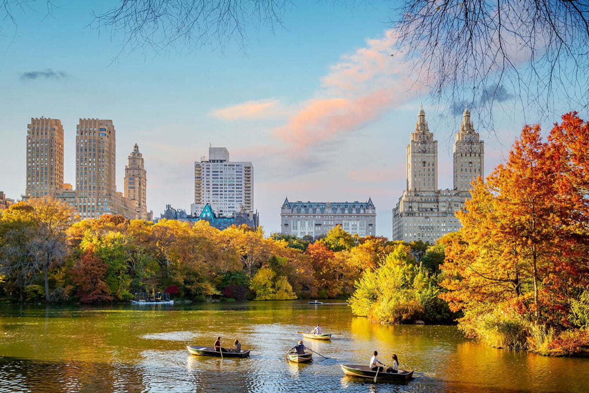 Boat riding in Central Park with luxury residential building in the back - on the Upper West Side.