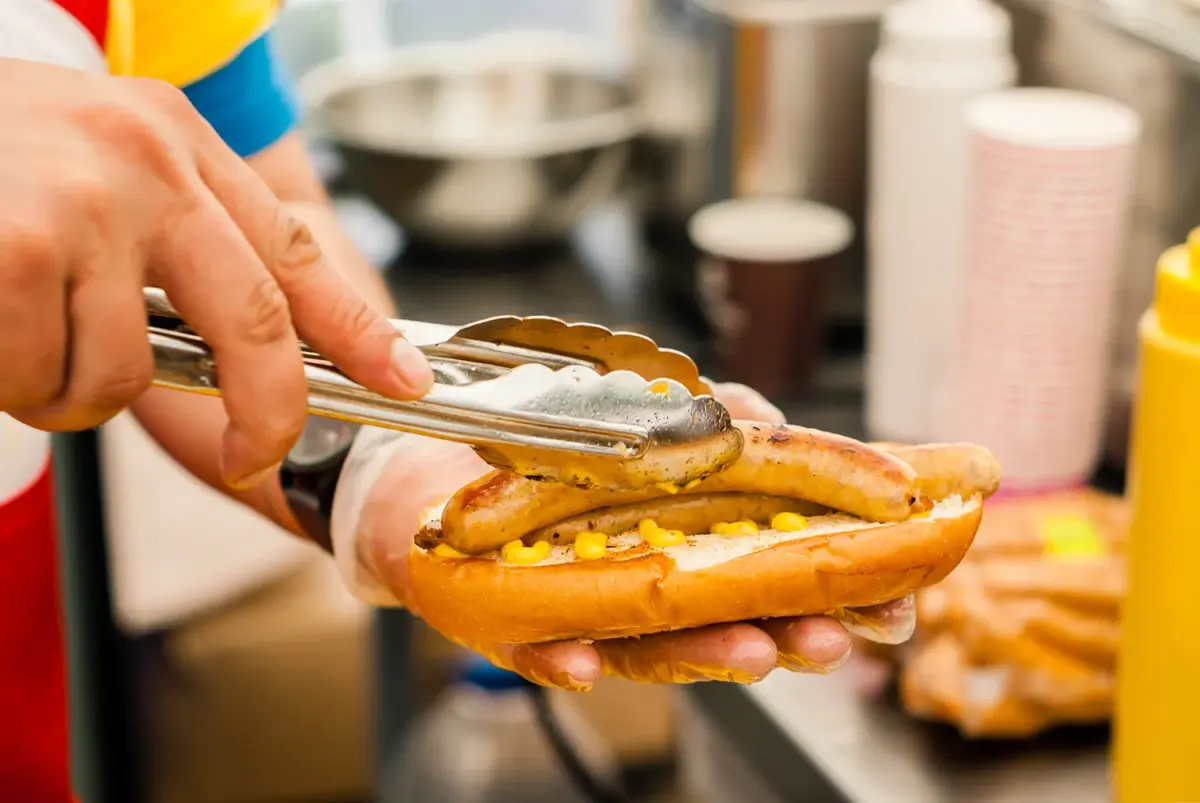 Closeup of hands serving a hotdog at food event NYC - Queens Taste 2023