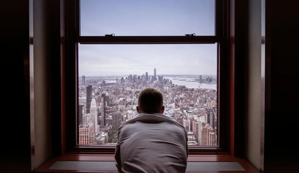 Man looking out of window from a Manhattan residential building